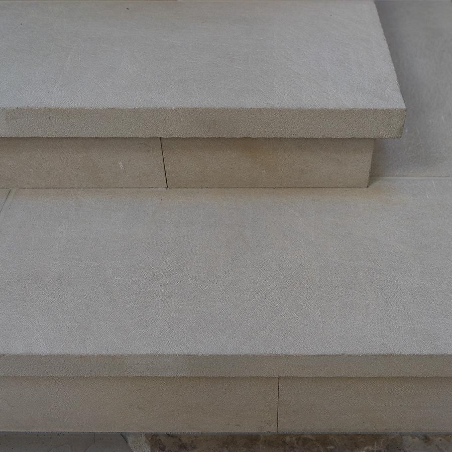 Close-up of Plaza Buff limestone stair tread with bush-hammered finish, showcasing its light brownish, sandy texture and ideal grip for safe stepping.