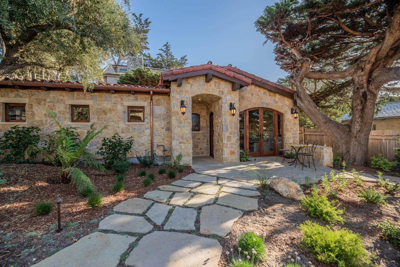 A charming stone-clad home with a rustic flagstone walkway, blending natural beauty with timeless architectural elegance.