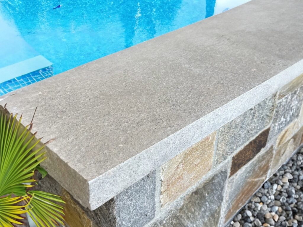 Detailed view of premium Pewter Limestone wall coping with anti-slip flamed texture, showcasing earthy grey and cream tones, ideal for outdoor architectural designs.