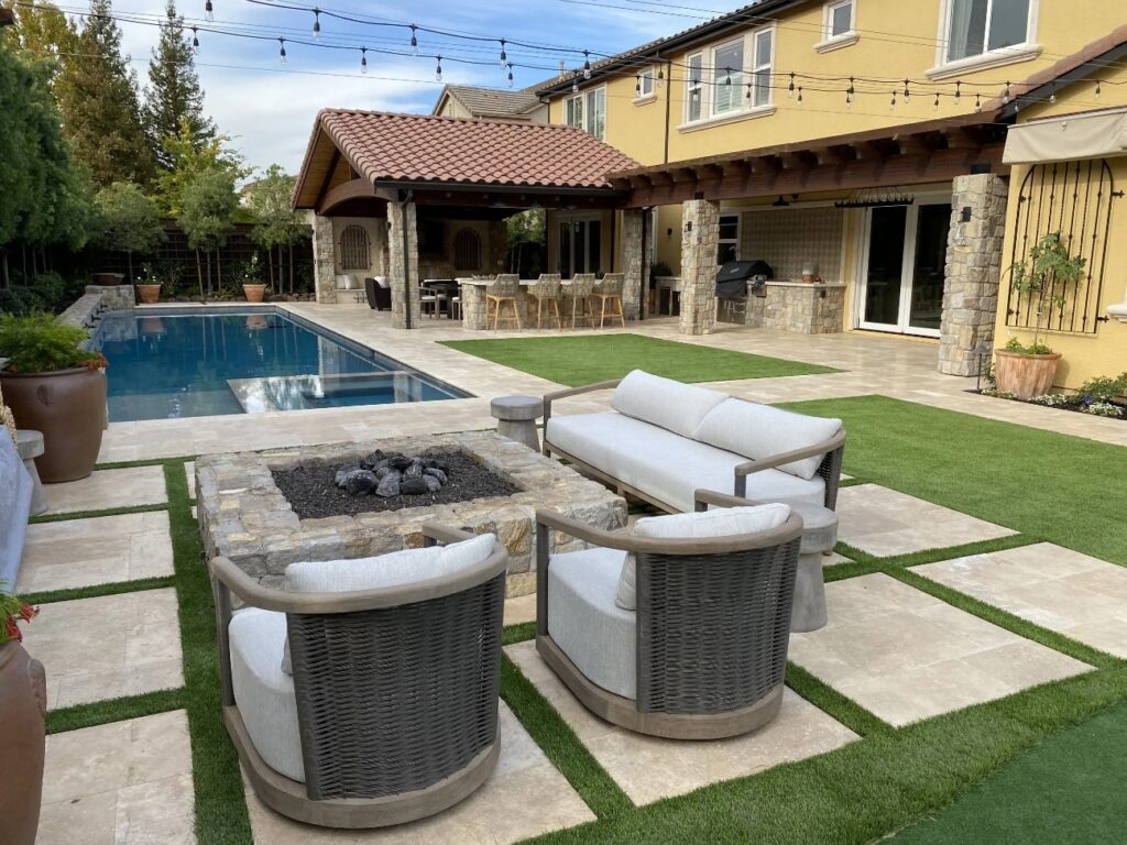 Eco-friendly design of travertine pavers with grass in between, creating a natural and sustainable patio space, showcasing versatile outdoor landscaping options from Peninsula Building Materials.