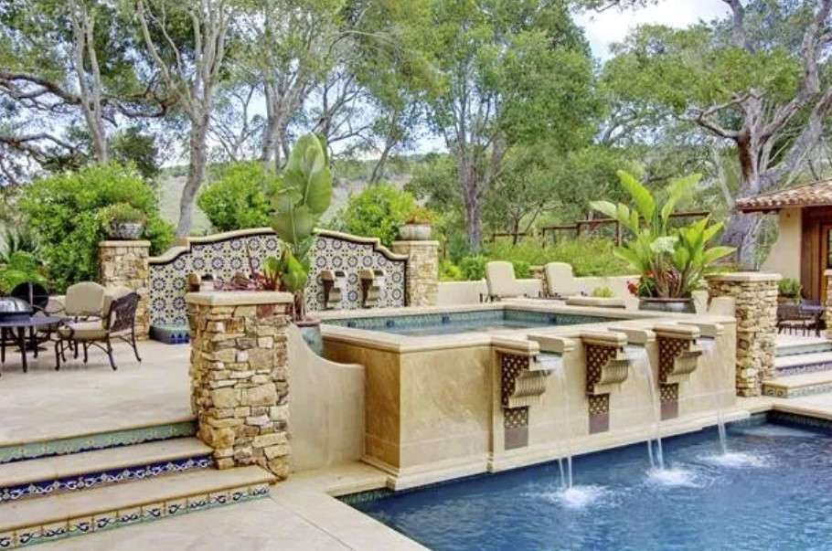 Innovative fountain design using travertine pavers at the front of a pool, with cascading water enhancing the tranquil outdoor environment, crafted from premium travertine stones.