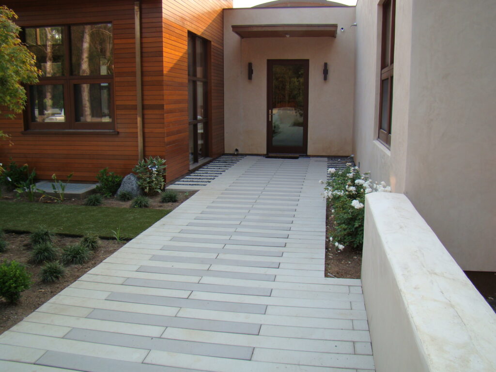 Elegant walkway using alternating grey and white pavers leading to the back door of a house, showcasing a cohesive and stylish hardscape design ideal for modern landscapes.