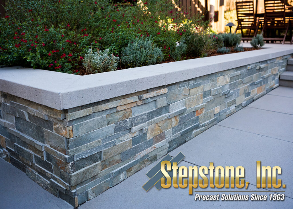 Elegant back patio short wall featuring natural stone veneer and a precast paver wall cap by Stepstone Inc., enhancing the functionality and aesthetic of the outdoor area with durable, low-maintenance materials.