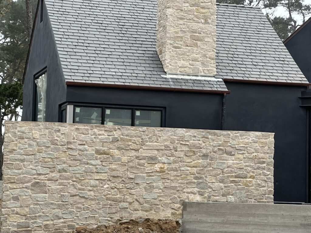 Natural stone veneer wall featuring Tundra Cream Rubble limestone, seamlessly blending with the architecture of two adjacent homes.