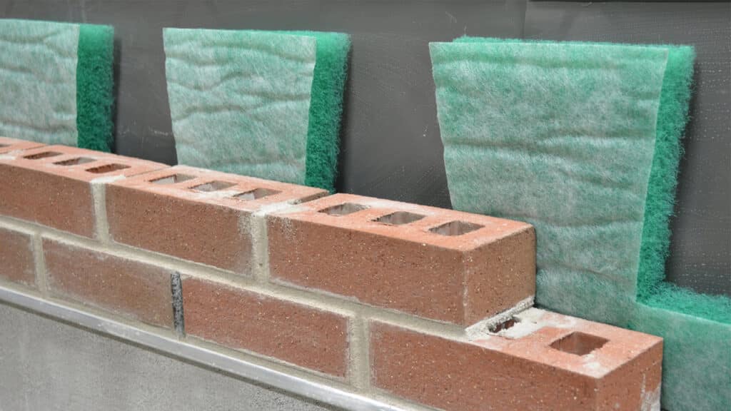 Close-up of MortarNet™ with Insect Barrier™ installed behind brick masonry, showing its moisture management and ventilation capabilities in cavity walls.