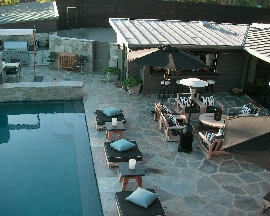 Luxurious infinity pool surrounded on three sides by a natural flagstone patio, blending seamlessly with the outdoor landscape.