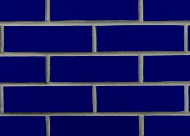 A striking wall of deep blue glazed bricks with contrasting white mortar, highlighting a bold and modern architectural trend.