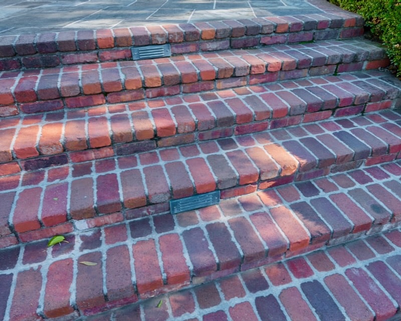 A classic set of red brick steps leading to a natural stone landing, blending traditional and contemporary design elements.