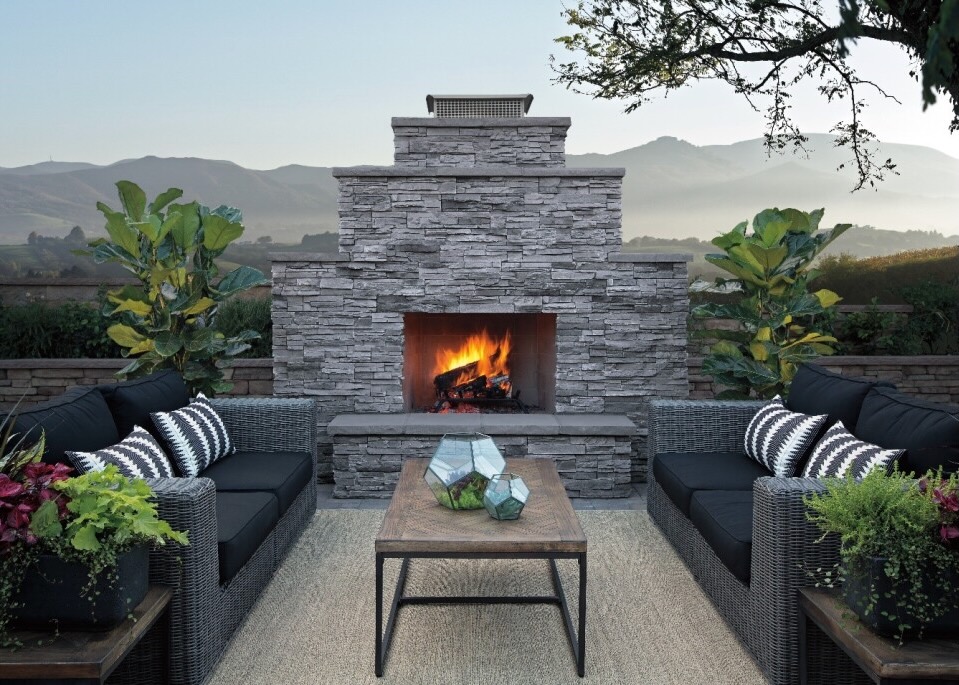 Rustic outdoor natural stone fireplace paired with modern patio furniture, creating a cozy and stylish backyard retreat.