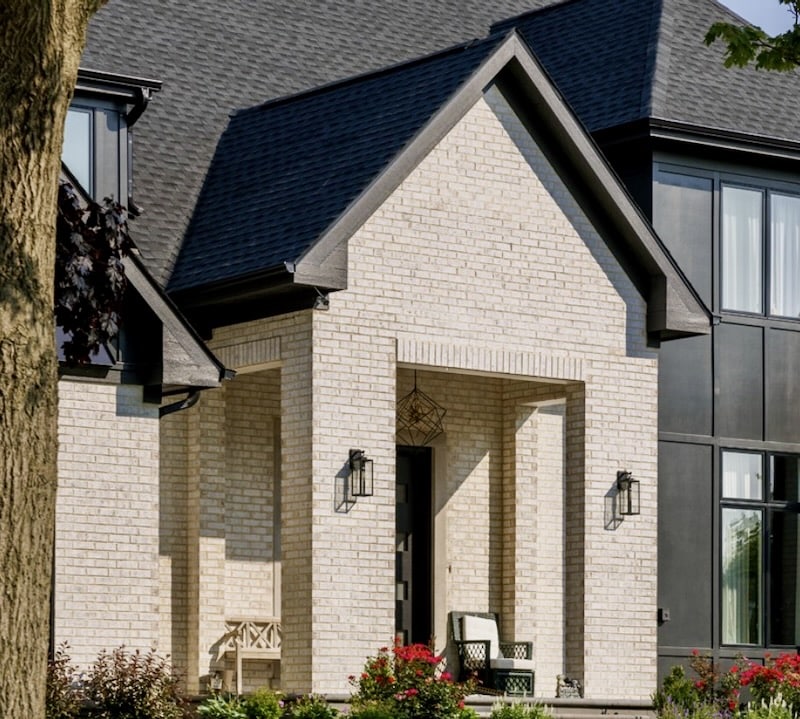 A modern home entrance featuring white brick with black trim and roof accents, creating a stylish and sophisticated curb appeal.