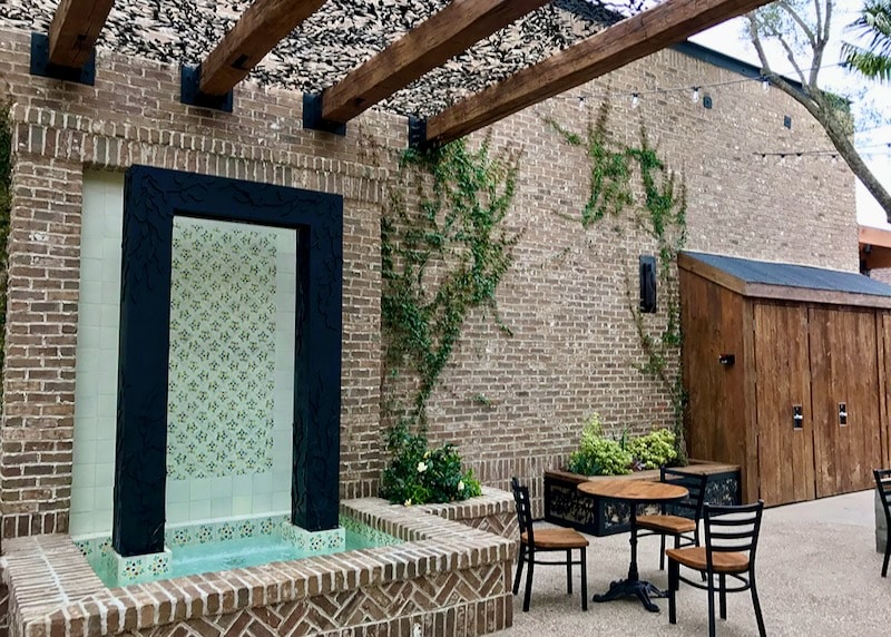 A stylish outdoor courtyard featuring a brick veneer wall with a decorative fountain and pergola, illustrating the aesthetic and fire-resistant benefits of brick construction.