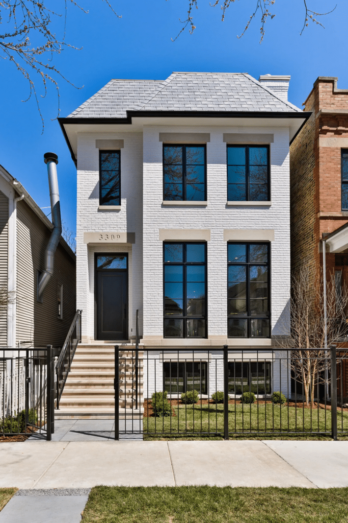 Urban two-story home featuring white painted brick, symmetrical windows, and modern black trim, demonstrating a clean and updated traditional style.