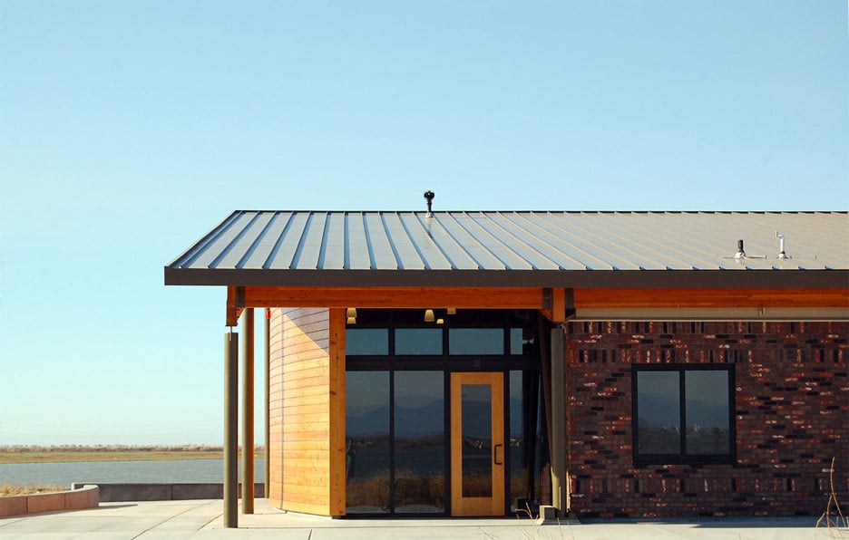 ward-winning modern building featuring a mix of red brick and wood siding with a metal roof, demonstrating sustainable architectural material integration.