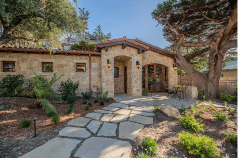 Beautiful home exterior featuring warm-toned natural flagstone walkway leading to the entrance, surrounded by landscaping.