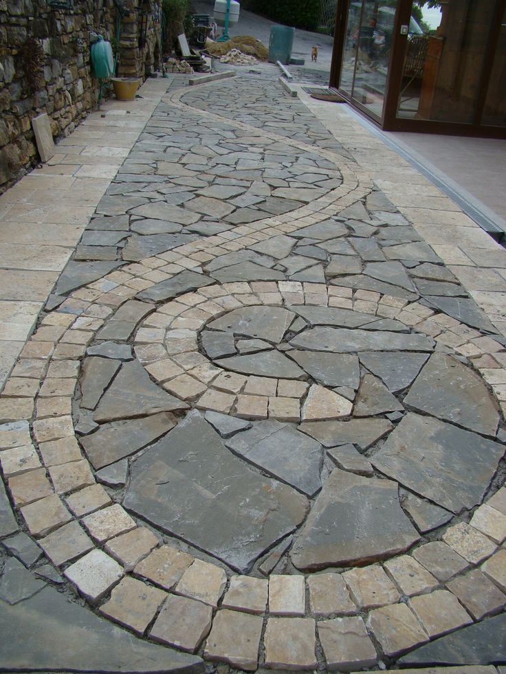 Creative flagstone walkway design featuring a circular pattern with contrasting light and dark grey natural stone.