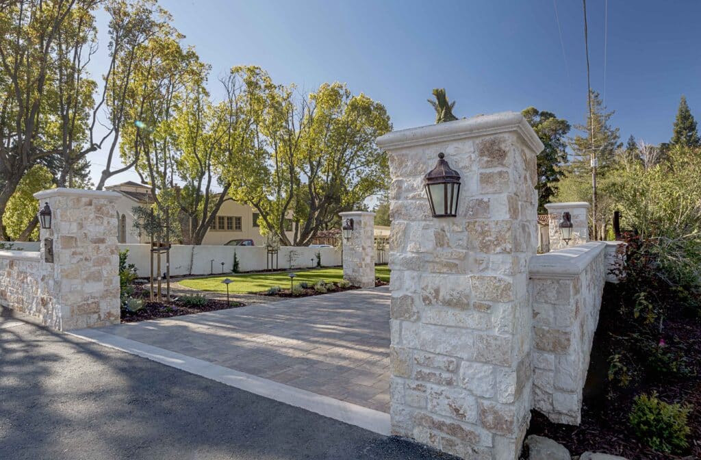 Natural stone columns with lantern lights framing a driveway entrance for upscale curb appeal.