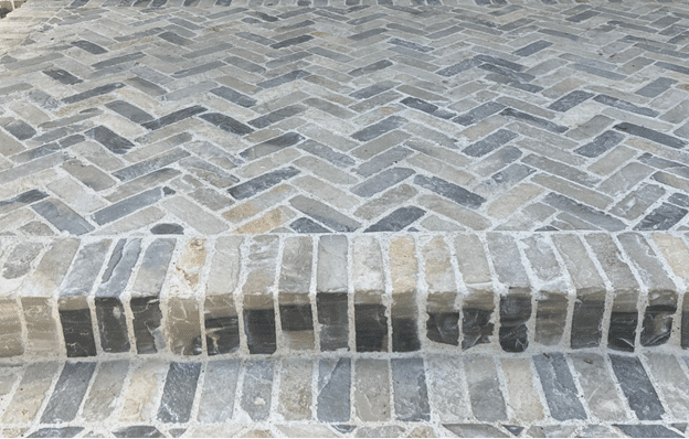 Elegant herringbone natural stone paving with matching steps, enhancing outdoor curb appeal.