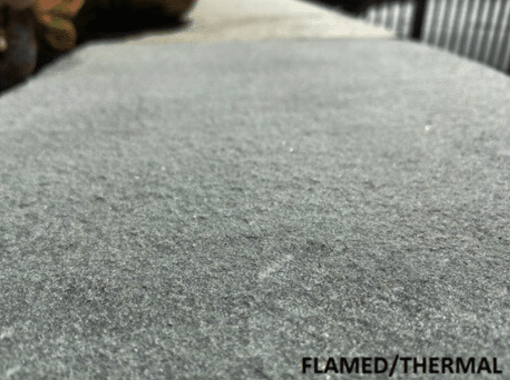 Close-up of gray flamed or thermal-finished stone showing a fine, gritty slip-resistant texture.