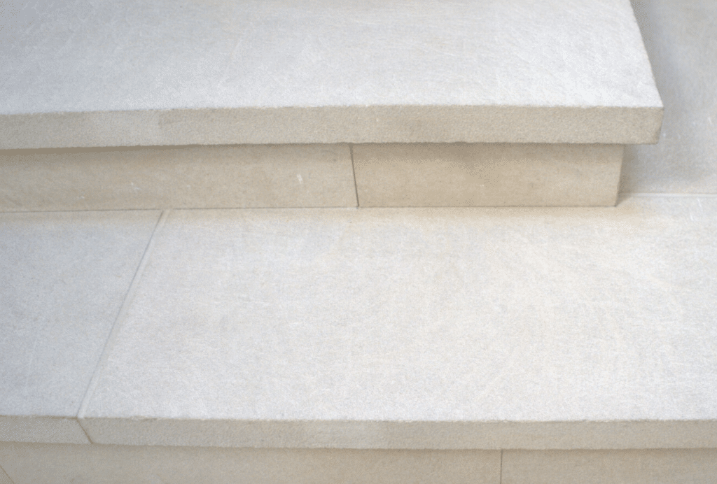 Detail of light limestone steps with clean sawn edges and a subtly textured, matte surface.