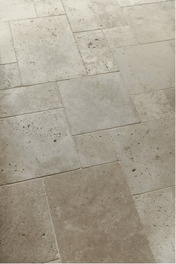 Beige honed and lightly pitted stone floor tiles laid in a random rectangular pattern.