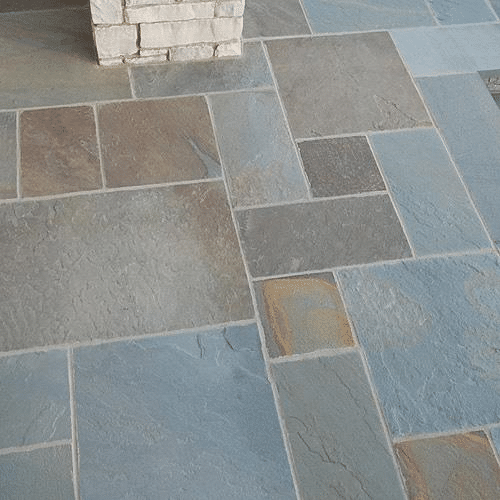 Multicolored natural cleft stone patio with rectangular and square pavers in blues, grays, and earth tones.