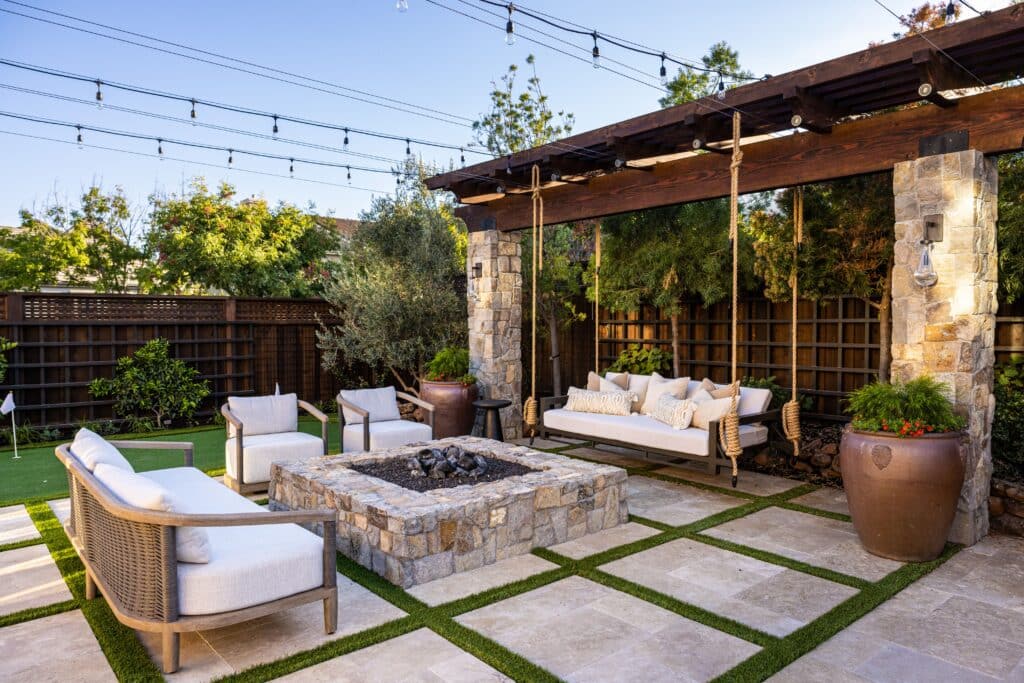 Willow Creek stone pillars and matching fire pit on a Napa-style indoor-outdoor patio with pergola, string lights, and lounge seating.