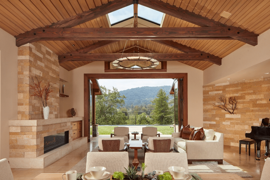 Plaza Gold limestone fireplace wall and accent wall in a vaulted-ceiling Bay Area great room with open patio doors and hillside view.